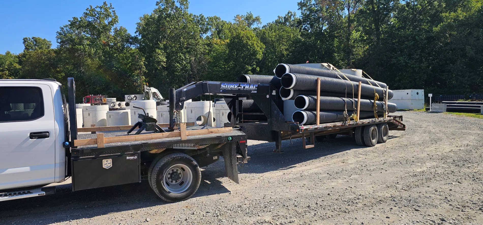 Black drainage pipes loaded on a flatbed trailer for an excavation project