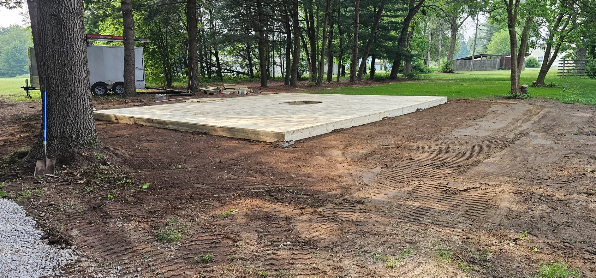 Freshly graded dirt pad with timber border prepared for a backyard shed foundation