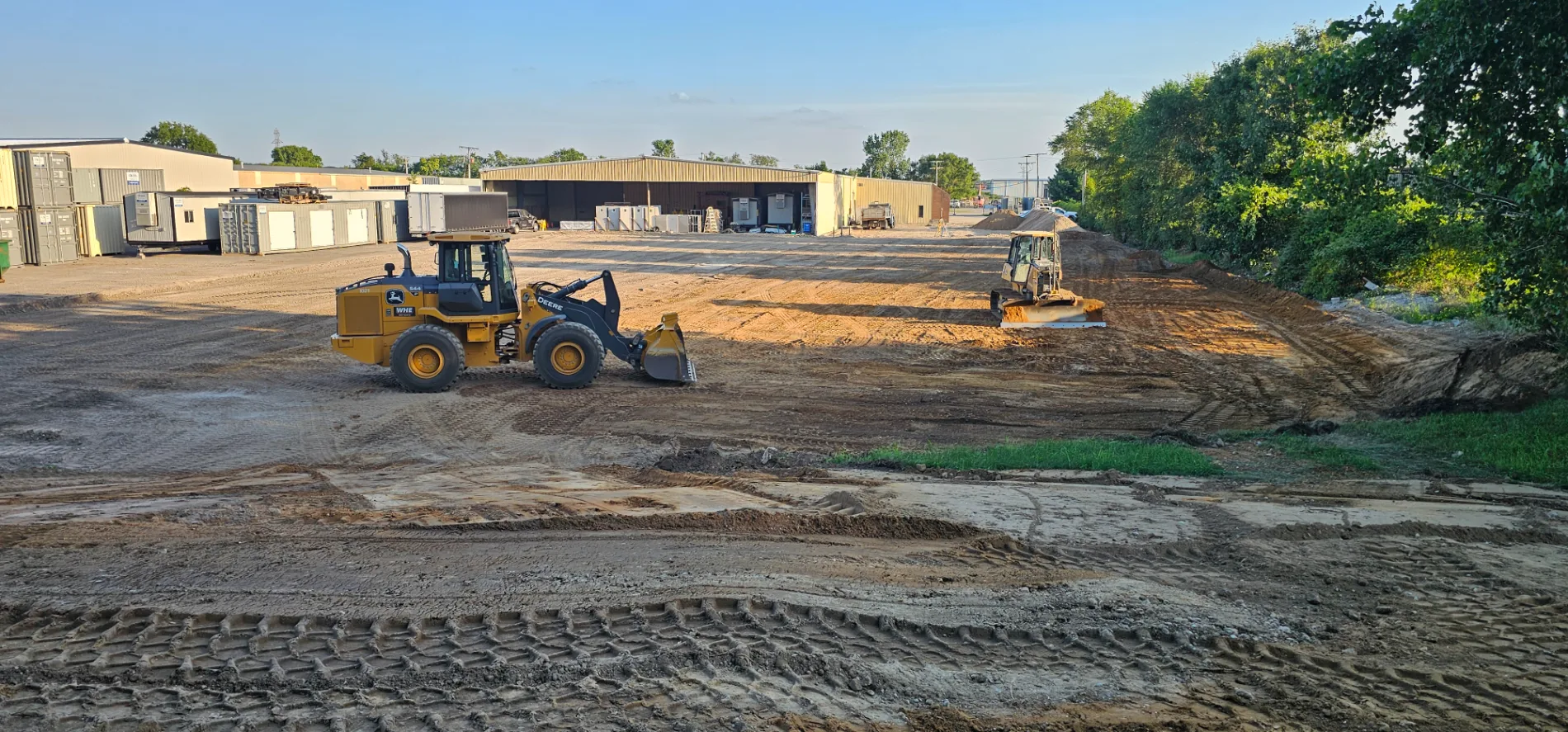 Yellow loader and bulldozer clearing land at a commercial excavation site
